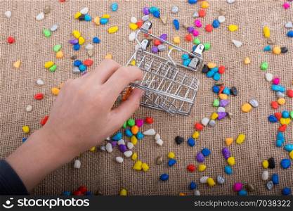 Little trolley amid Colorful pebbles on canvas background