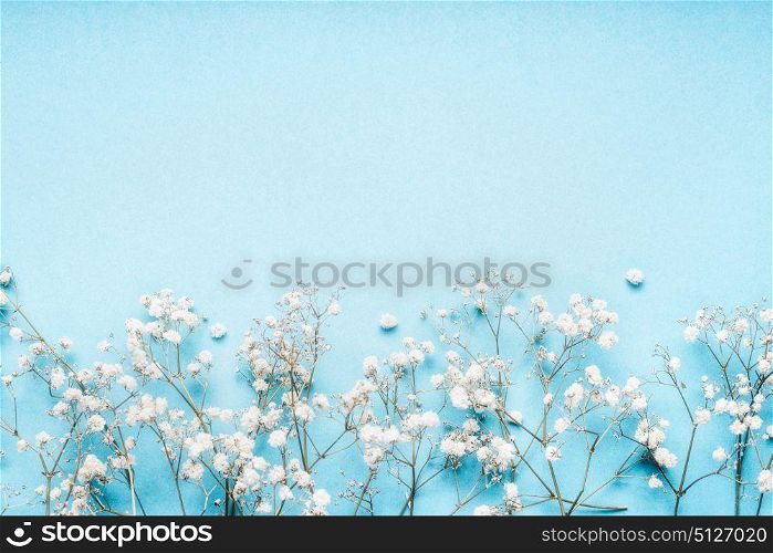 Little white Gypsophila flowers on blue background, pretty floral border, top view, copy space, horizontal