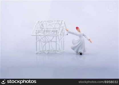 Little wired metal model house and a Sufi dervish. Sufi dervish and a little metal house on a white background