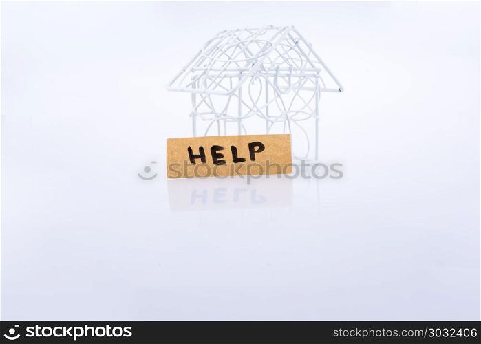 Little wired metal model house and the word HELP. Little metal house and the word HELP on a white background