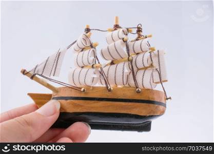 Little woodenl model boat in hand on white background
