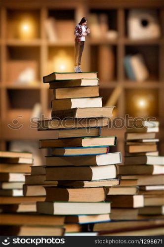 Little young woman standing on mountain of large books and textbooks, scale effect. Knowledge and education, reaiding concept. Woman standing on mountain of large books