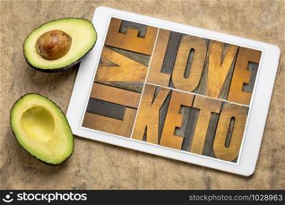 live, love keto, high fat ketogenic diet concept - word abstract in vintage letterpress wood type on a digital tablet with cut avocado