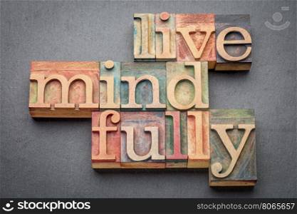 live mindfully - word abstract in letterpress wood type against gray slate stone