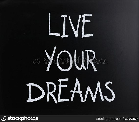 ""Live your dreams" handwritten with white chalk on a blackboard."
