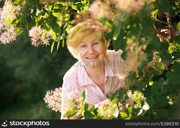 Lively Cheerful Optimistic Senior Woman among Flowers
