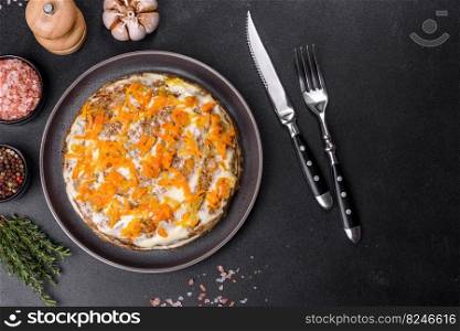 Liver cake with meat and egg, hea<hy protein food, rustic sty≤. Delicious fresh liver cake with mayonnaise and carrots on a black plate against a dark concrete background
