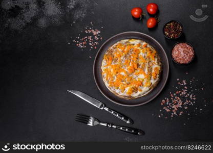 Liver cake with meat and egg, healthy protein food, rustic style. Delicious fresh liver cake with mayonnaise and carrots on a black plate against a dark concrete background