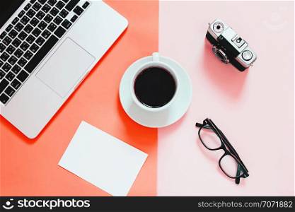 Living Coral color background, Color of the year 2019, flat lay of workspace desk with laptop, blank paper, coffee, eyeglasses and camera