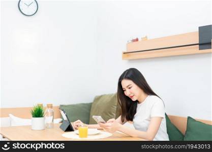 Living room concept a girl with long hair sitting in the living room surfing the internet with her smartphone.