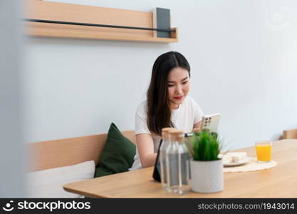 Living room concept a girl with long hair sitting in the living room surfing the internet with her smartphone.