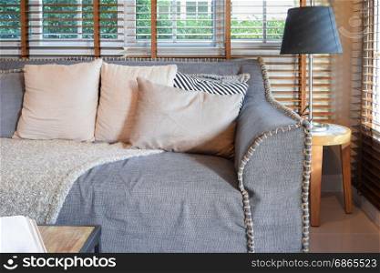 living room interior with pillows on sofa and decorative wooden table with lamp