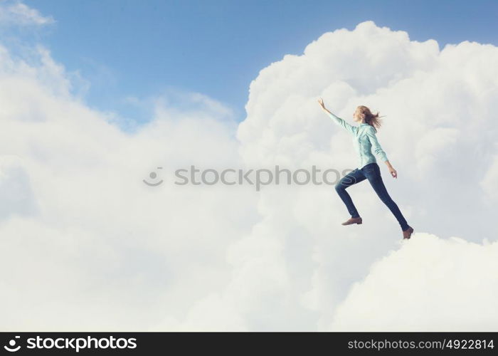 Living with faith. Young woman high in sky reaching up