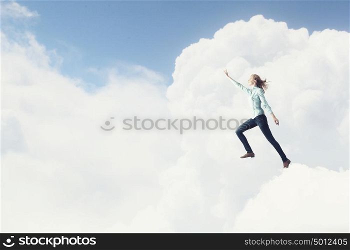 Living with faith. Young woman high in sky reaching up