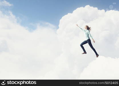 Living with faith. Young woman high in sky reaching up