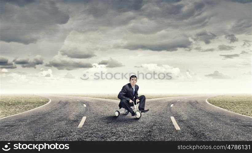 Lke a child. Young handsome businessman riding three wheeled bicycle
