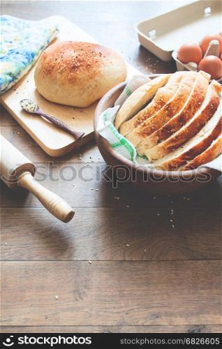 loaf of bread on wood background with eggs and bakery tools with copy space