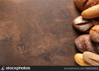 Loaf of fresh bread and buns on table. Assortment of bakery food at stone  tabletop background texture with copy space. Flat lay top view