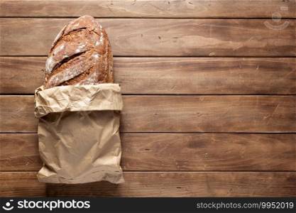 Loaf of fresh bread and buns on wooden table. Bakery food at wood plank board background texture with copy space. Flat lay top view
