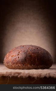 Loaf of rye bread on rustic background