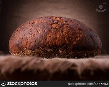 Loaf of rye bread on rustic background
