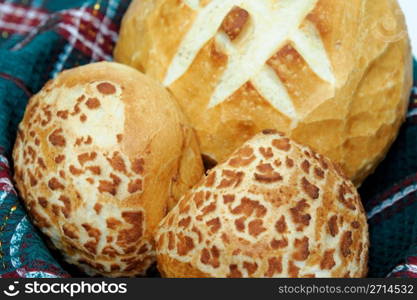 Loaf of sourdough bread and 2 rolls in a basket lined with a green cloth. Bread And Rolls