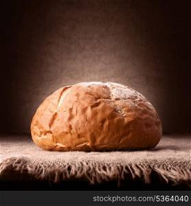 Loaf of wheat bread on rustic background