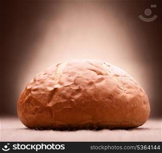 Loaf of wheat bread on rustic background
