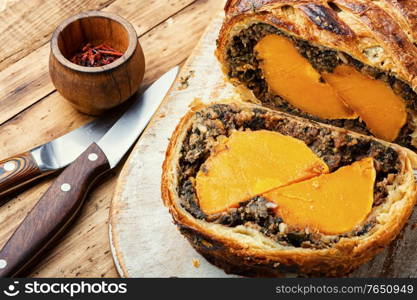 Loaf with baked pumpkin and mushrooms.Wellington pumpkin, autumn traditional food.. Roll stuffed with mushrooms and pumpkin.