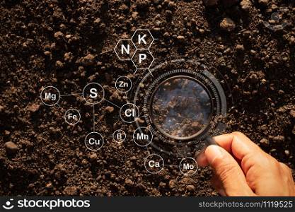 Loam that is rich in minerals and has a man&rsquo;s hand using a magnifying glass to research.