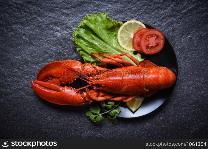 Lobster on plate seafood with lemon salad lettuce vegetable and tomato on dark background
