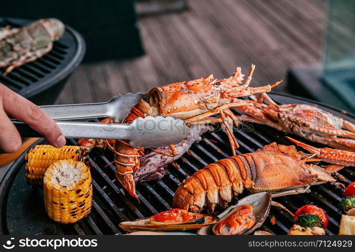 Lobster, rock lobster and mix seafood barbecue cokking on grill - seafood dinner party concept