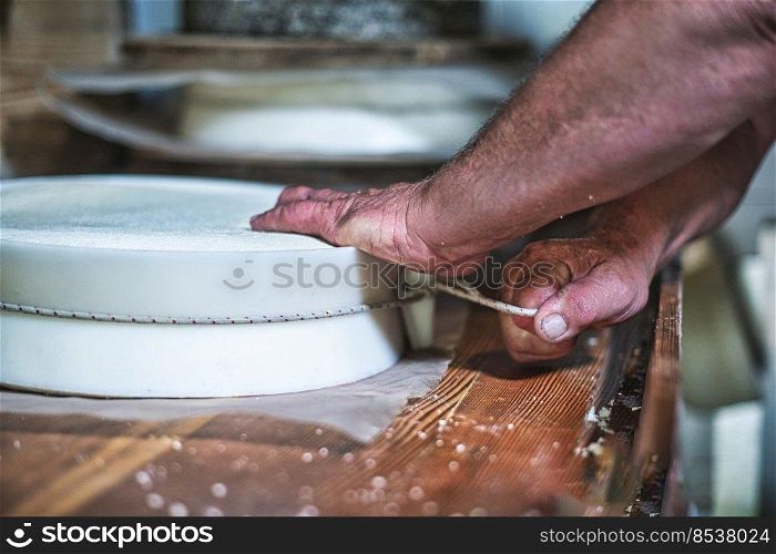 Local cheese peoduction. Tie of string to create the typical Bergamo Italian cheese shape
