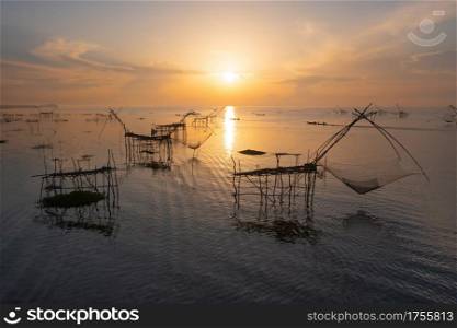 Local fishing trap net in canel, lake or river at sunset. Nature landscape fisheries and fishing tools lifestyle at Pak Pha, Phattalung, Thailand. Aquaculture farming.