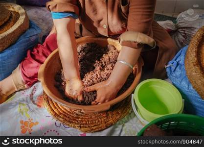 Local Moroccan woman hand-kneading argan oily paste in order to extract Argan oil. Essaouira, Morocco.