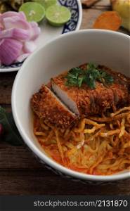 Local northern Thai food Egg noodle curry with fried pork on wood background