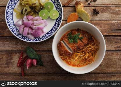 Local northern Thai food Egg noodle curry with fried pork on wood background