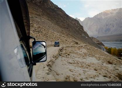 Local Pakistani people driving off-road vehicle along dirt road in the mountain in Karakoram range in Passu, Gojal Hunza. Gilgil Baltistan, Pakistan.