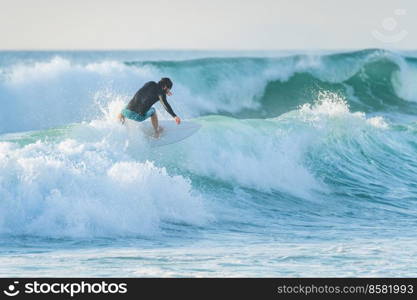 Local surfer riding waves with a short board in Furadouro beach, Portugal. Men catching waves in ocean. Surfing action water board sport.