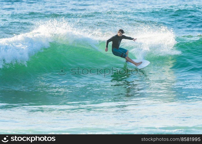 Local surfer riding waves with a short board in Furadouro beach, Portugal. Men catching waves in ocean. Surfing action water board sport.