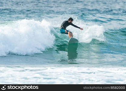 Local surfer riding waves with a short board in Furadouro beach, Portugal. Men catching waves in ocean. Surfing action water board sport.