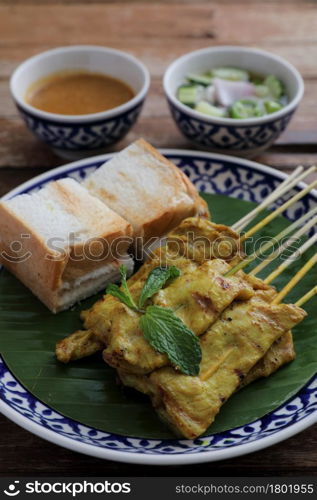 Local Thai food pork satay with oeanut dipping sauce isolated in wood background