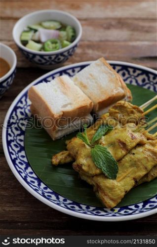 Local Thai food pork satay with oeanut dipping sauce isolated in wood background