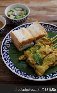 Local Thai food pork satay with oeanut dipping sauce isolated in wood background