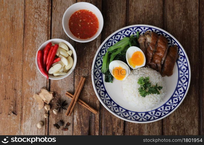 Local Thai food stewed pork leg on rice isolated in wood background