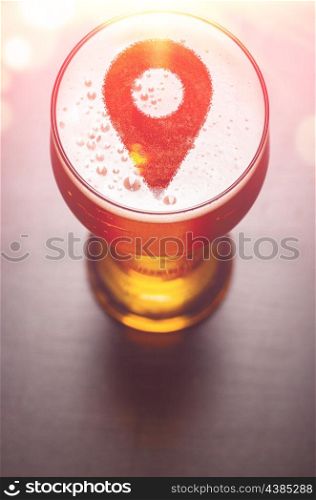 location pin symbol on foam in glass on black table, view from above