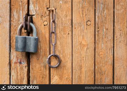 Locked old wooden door with a lock and metal chain