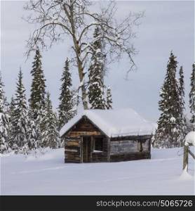 Log cabin in snow covered forest, British Columbia Highway 97, British Columbia, Canada