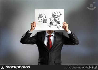 Logic thinking. Businessman hiding his face behind paper with drawing