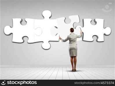 Logic thinking. Rear view of businesswoman connecting white puzzle